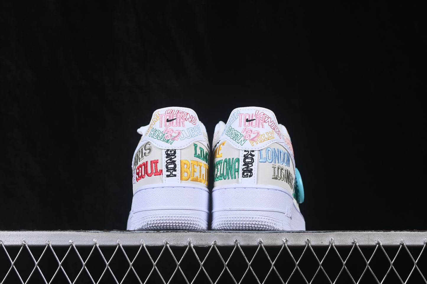 Custom white low-top sneaker featuring colorful city-inspired embroidered graphics and a lace-up design.
