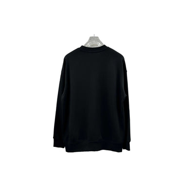 Black sweatshirt hanging on a rack against a textured wall