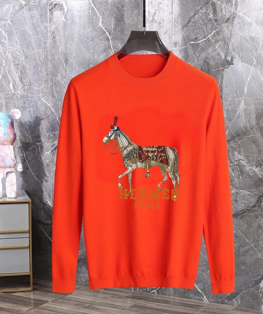 Orange sweater with embroidered horse design on a hanger against a marble wall.