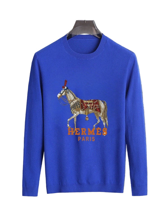 Blue sweater withgraphic on a hanger against a marble wall.