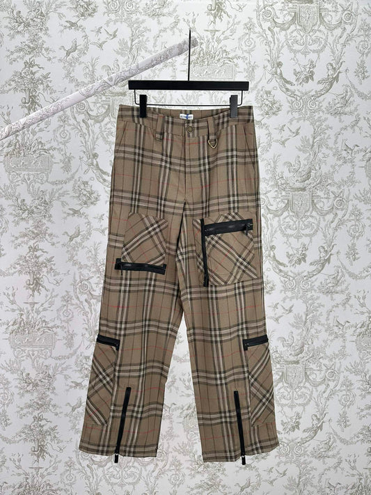 Statement cargo pants featuring an all-over plaid pattern, multiple utility pockets, and zippered accents throughout. Designed with a tapered fit and adjustable ankle zippers for a modern streetwear-inspired look.