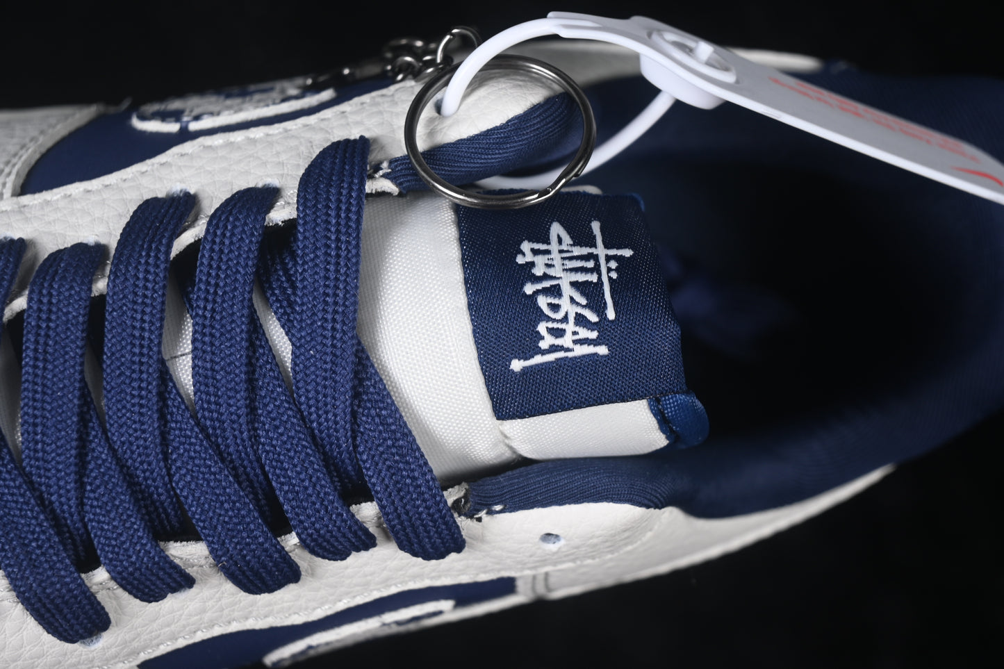White and navy low-top sneaker with perforated toe box, lace-up closure, cushioned sole, and rubber outsole displayed from a top angle.