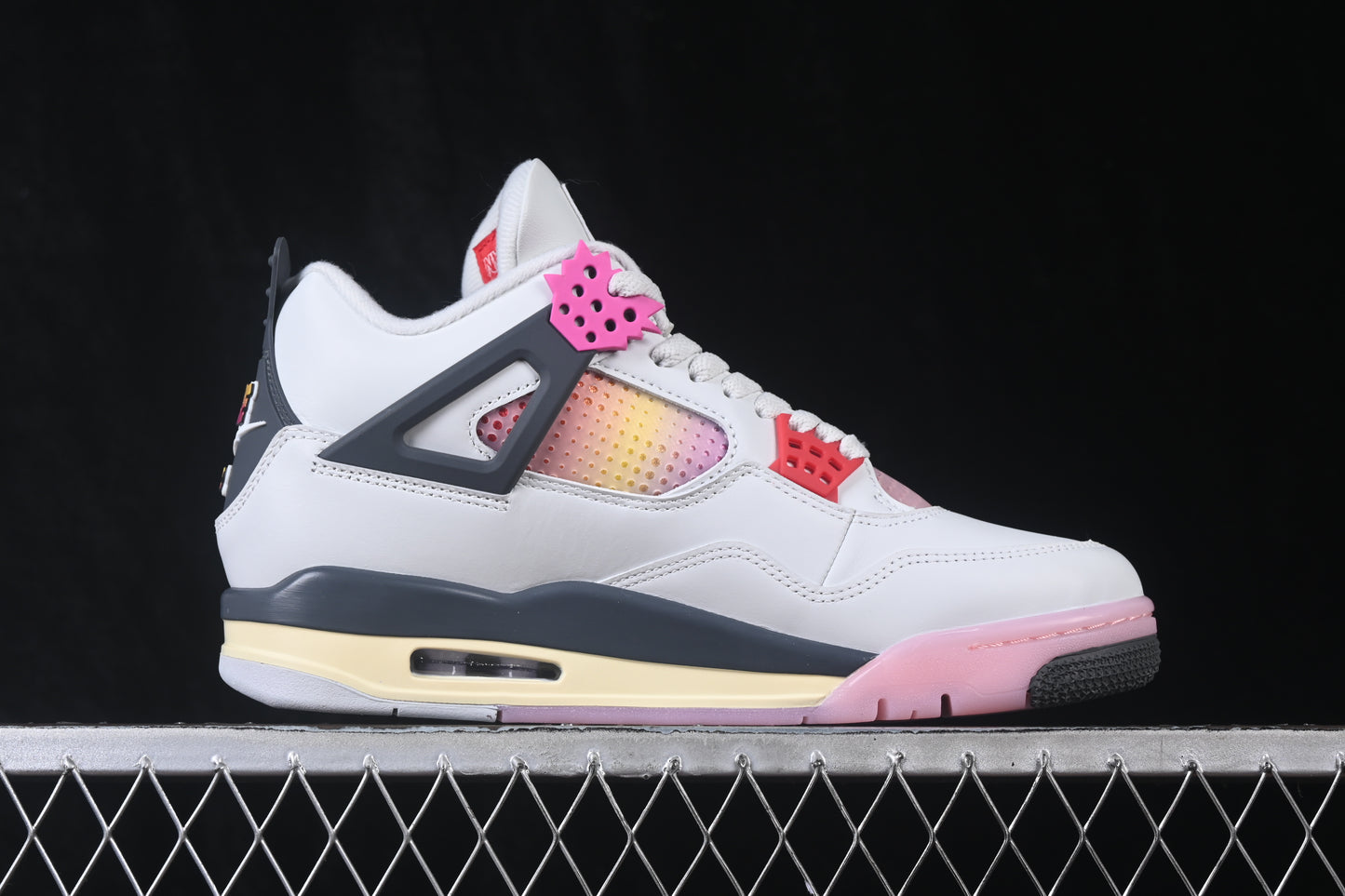 White retro basketball sneaker with pink accents, charcoal support panels, breathable mesh inserts, lace-up closure, and rubber outsole.