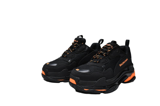Black  sneakers with orange accents and a matching box on a white background