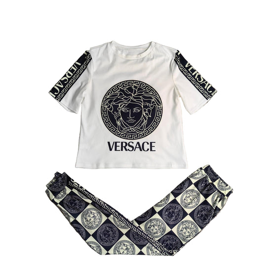 White t-shirt and patterned pants on a textured surface with a plant.