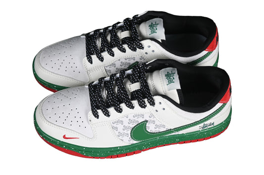 White sneakers with black, green, and red accents on a black chain-link fence background