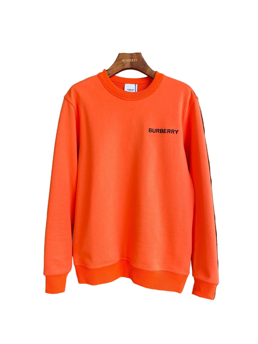 Orange sweatshirt with graphicon a hanger against a neutral background