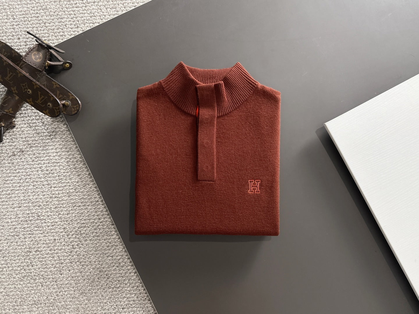 Folded brown polo shirt on a dark surface with a textured gray area.