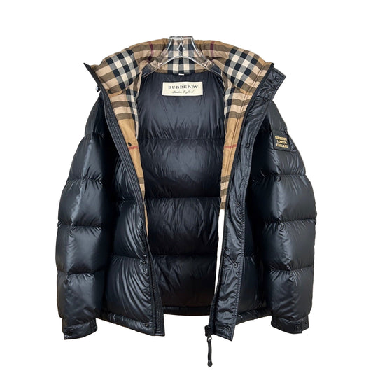 Black puffer jacket with plaid lining on a hanger against a neutral wall.