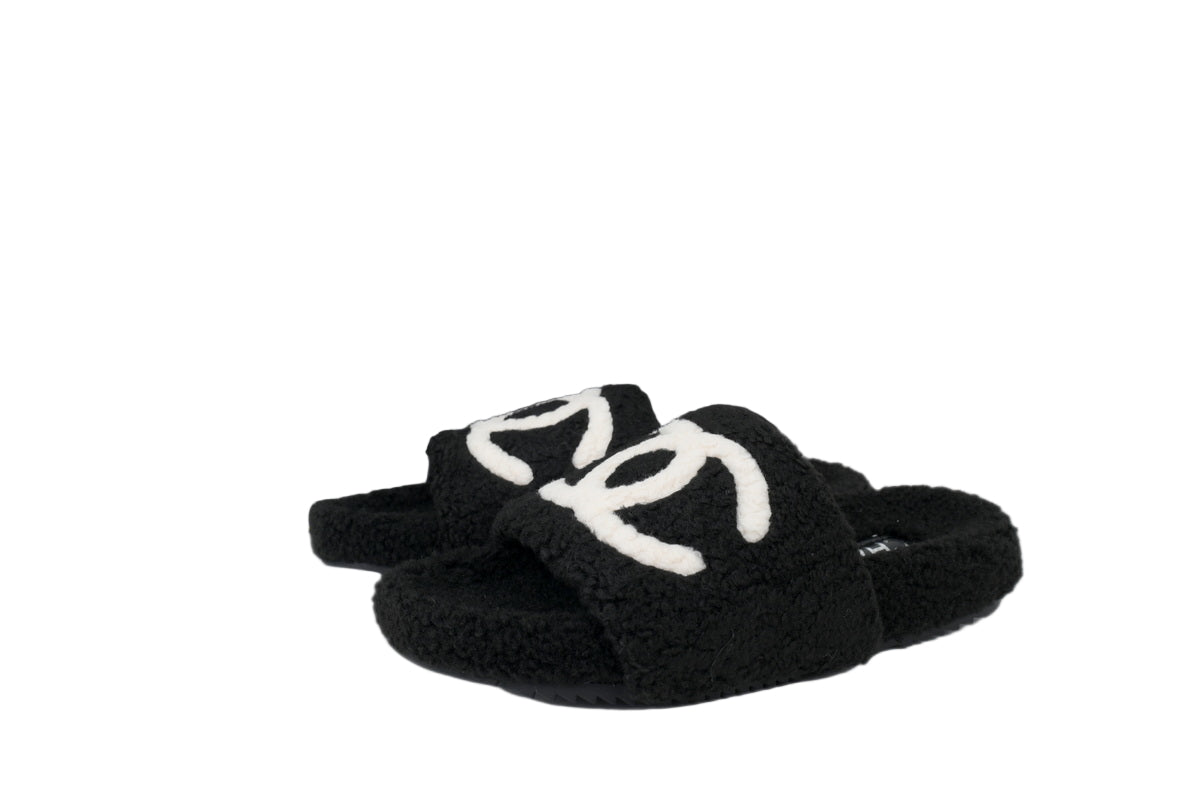Black CC slippers with white graphic on a white background
