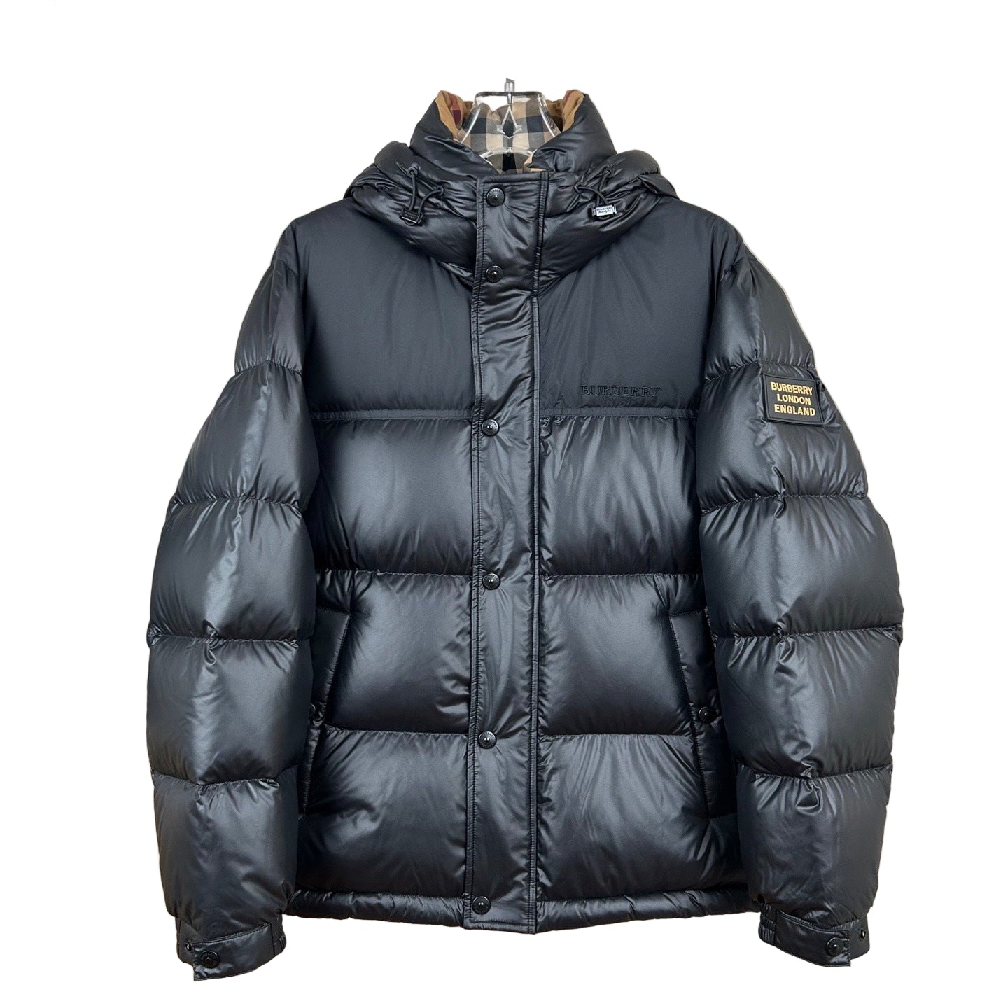 Black puffer jacket on a mannequin against a neutral wall.