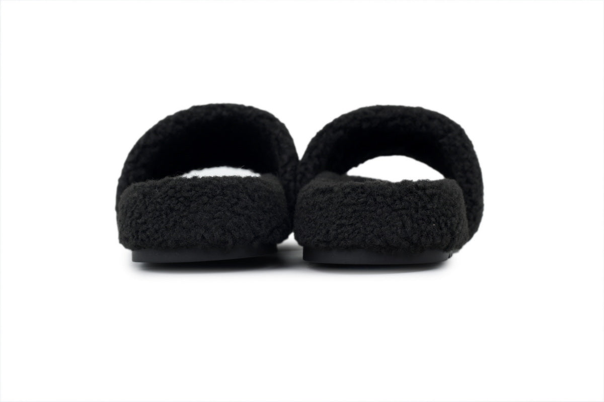 Pair of black slippers with fuzzy texture on a white background