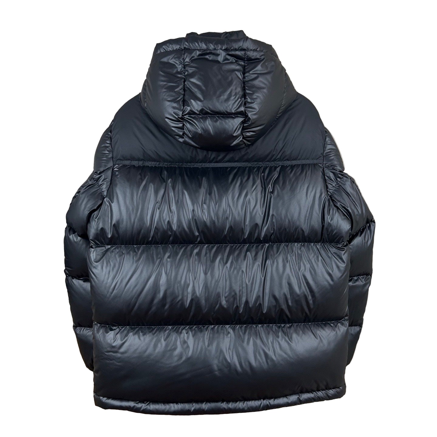 Black puffer vest hanging on a wall with a decorative lamp and shelf.