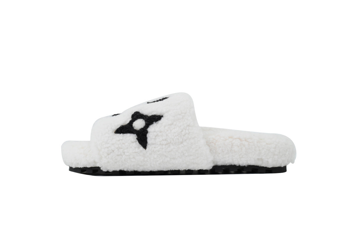 White fuzzy slide sandal with a black star design on a white background