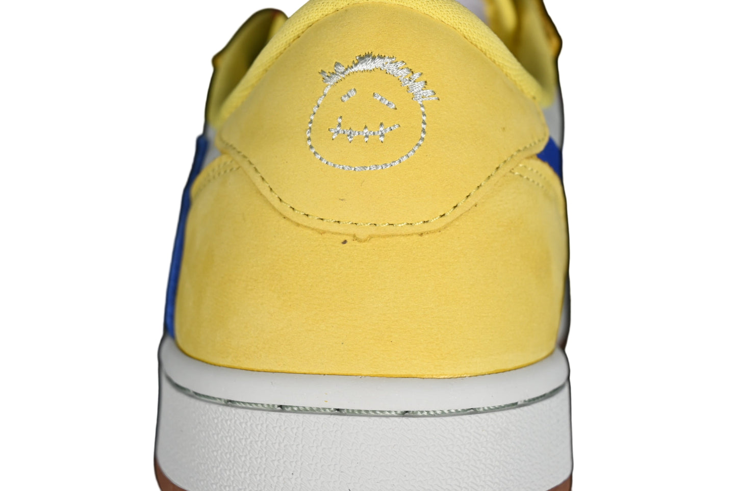 Yellow sneaker with a smiley face design on a black background