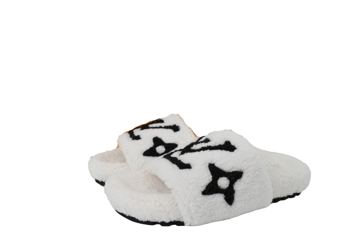 White slippers with black designs in front of abox on a white background