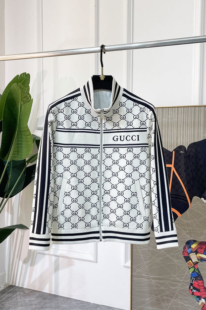 A  zip-up jacket featuring the brand's signature GG monogram pattern in black and white, hanging on a black hanger. The jacket has a white base with black monogram print, black and white striped ribbed collar, cuffs, and hem, and a black and white horizontal stripe across the chest with 'printed in black.