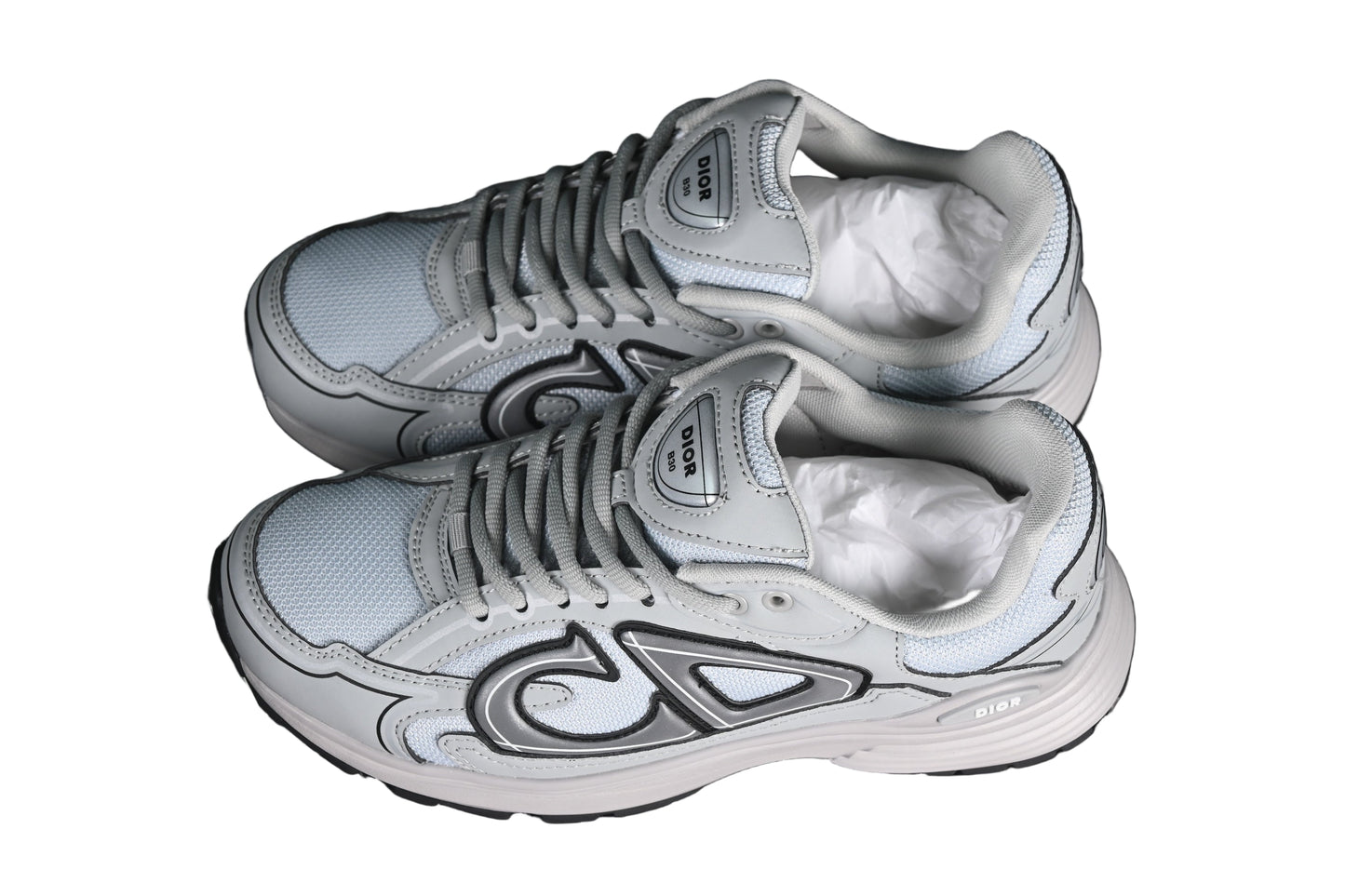 Pair of gray sneakers with white soles on a black grid background