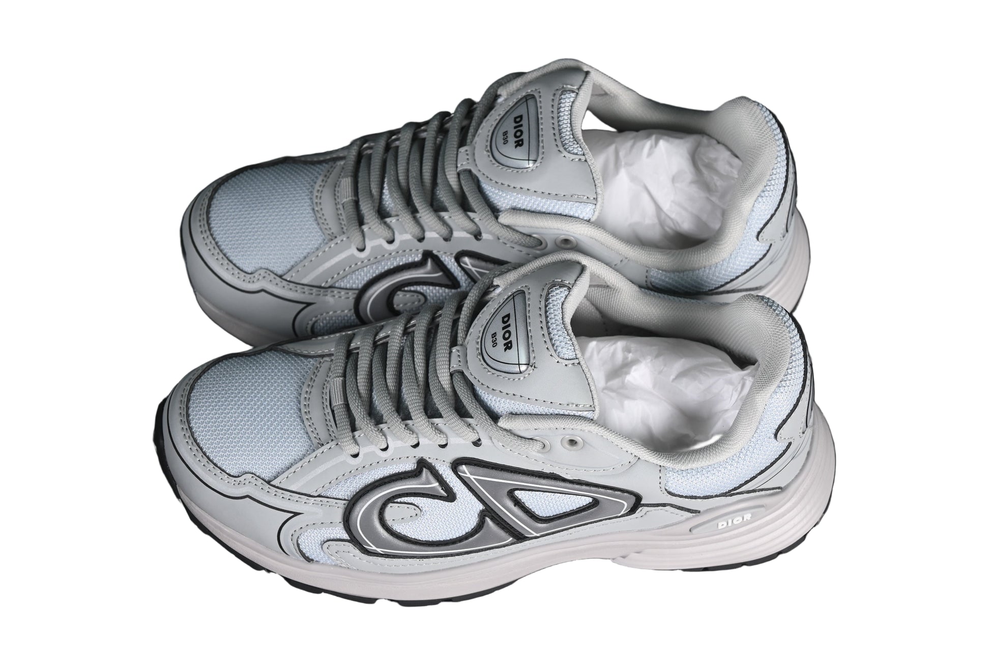 Pair of gray sneakers with white soles on a black grid background