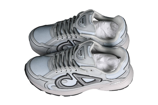 Pair of gray sneakers with white soles on a black grid background