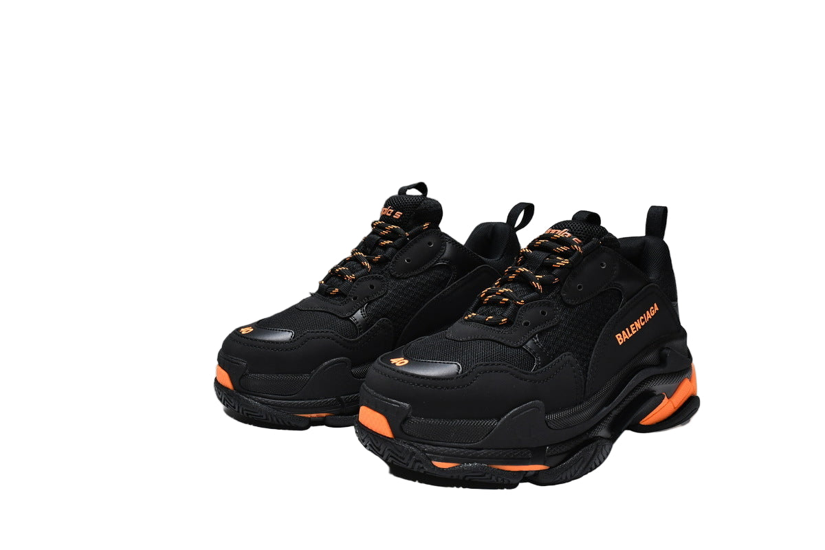 Black  sneakers with orange accents and a matching box on a white background