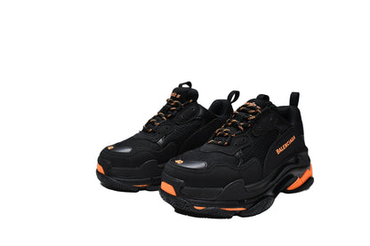 Black  sneakers with orange accents and a matching box on a white background