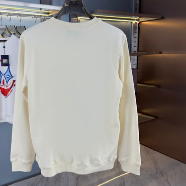 White sweatshirt with a colorful graphic on a hanger against a blue wall.