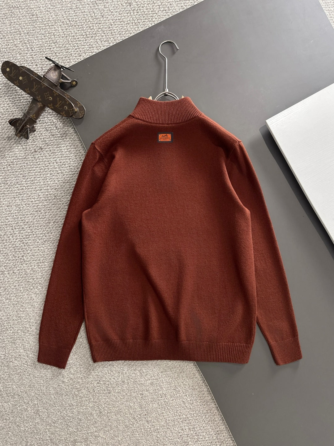 Brown sweater on a hanger against a neutral background
