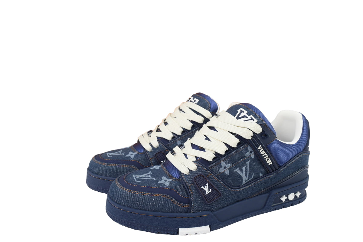 Blue sneakers with white laces and  displayed in front of an orange box.