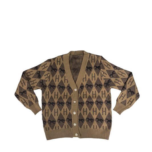 Brown patterned cardigan on a textured surface with a plant