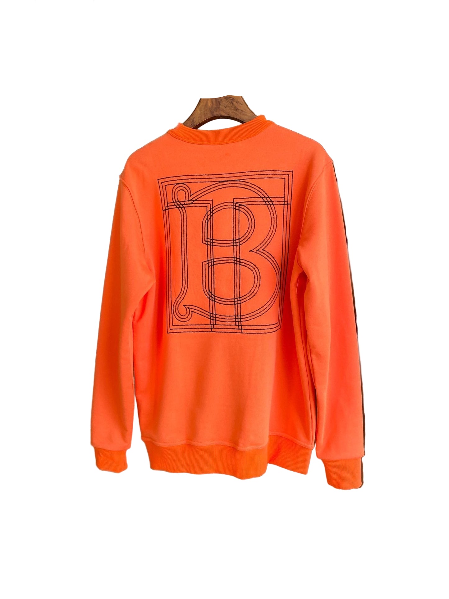 Orange sweatshirt with a logo on a hanger against a neutral background