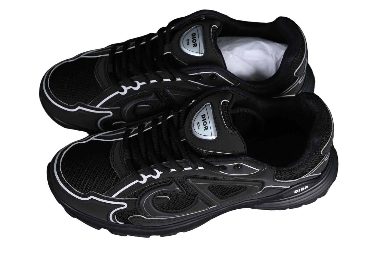 Black sneakers with white accents on a black grid background