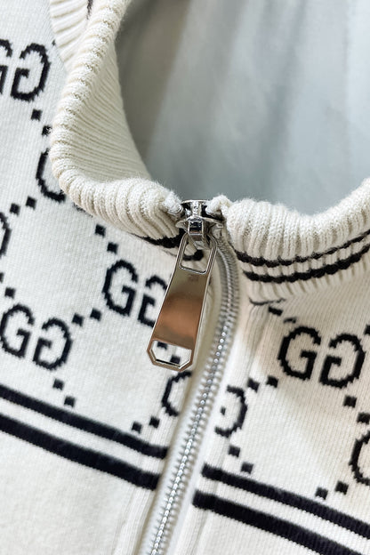 Close-up of a cream knit zip-up sweater with a black GG monogram pattern and a silver metal zipper.